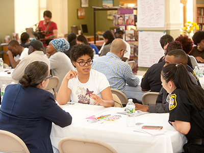 Community members and police talking around small tables together.